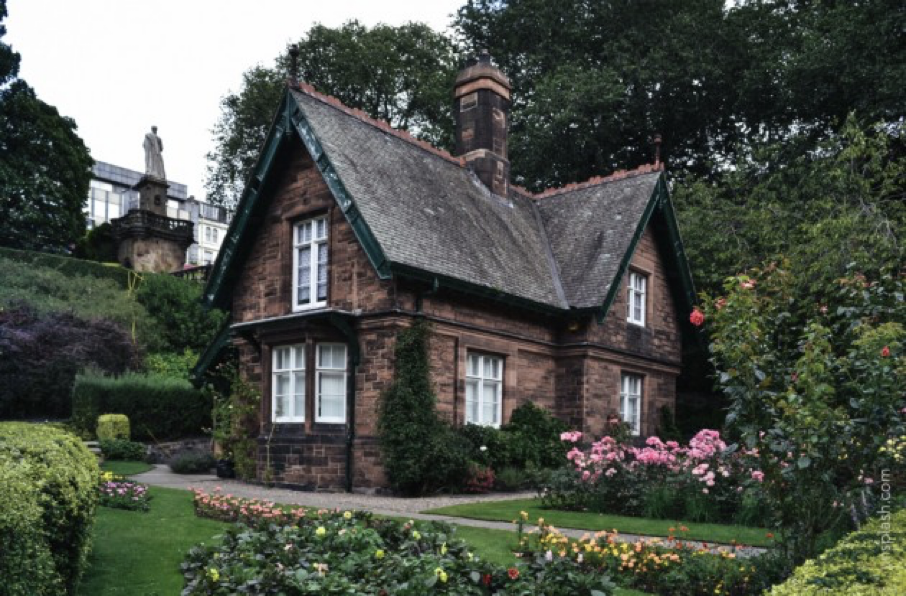 un cottage de campagne brun et rustique au milieu d'un jardin luxuriant