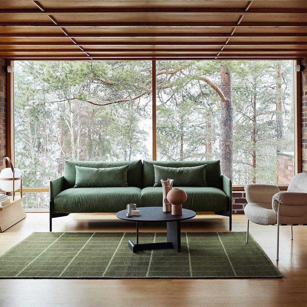 livng room with green carpet and couch with lage windows in the background