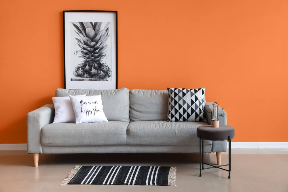 Stylish gray sofa with orange accent wall