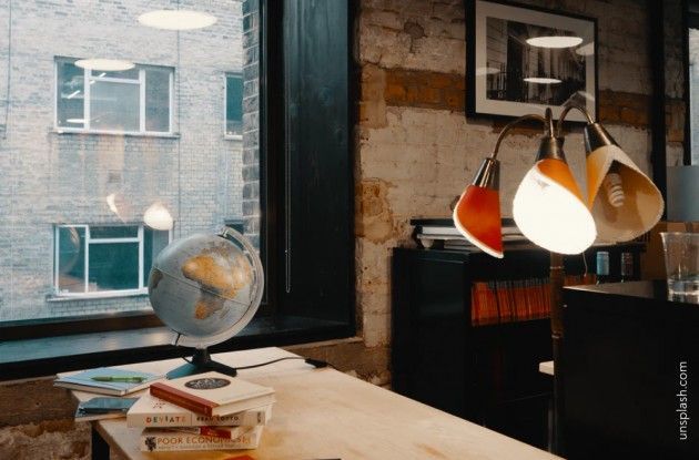 un bureau avec une globe, des livres et une lampe