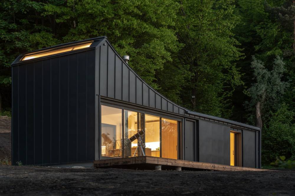 black container house with a deck in the woods