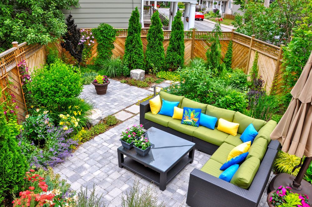 small, urban backyard garden featuring a tumbled paver patio, flagstone stepping stones, and a variety of trees, shrubs and perennials add colour and year round interest.