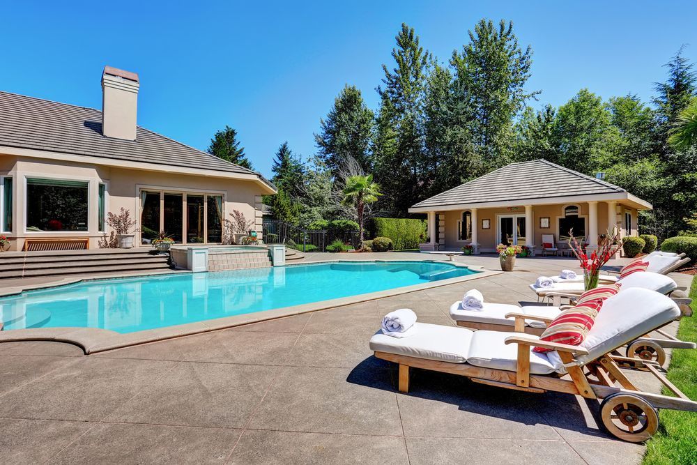 Great backyard with swimming pool and lounge chairs in American Suburban luxury house.