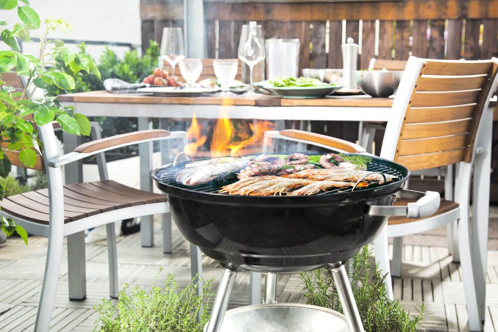 Close up of a charcoal grill with patio table and chairs