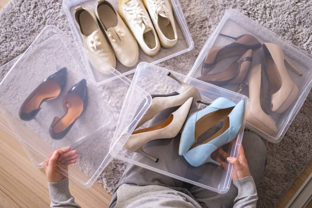 Hand holding clear storage boxes with shoes