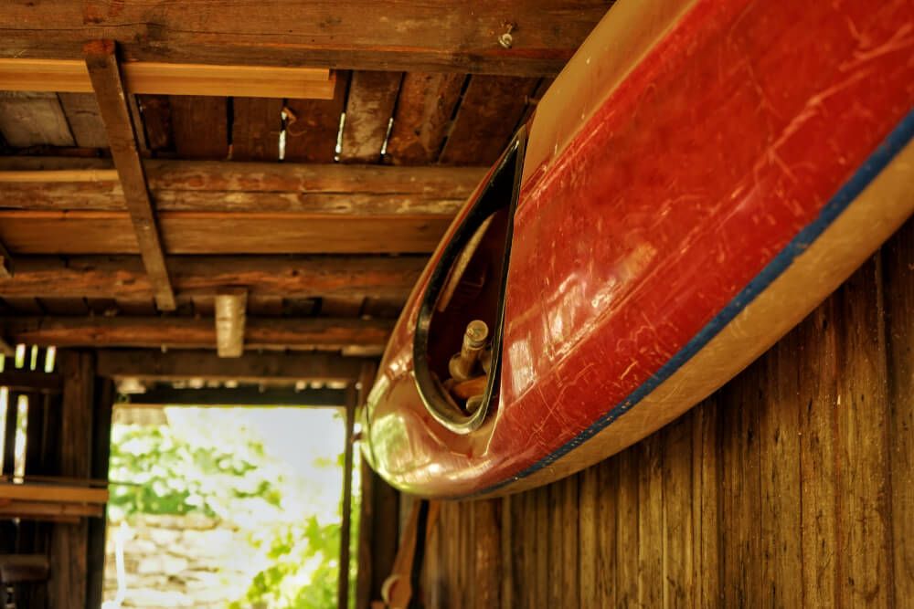 A red kayak mounted to the wall in a garage