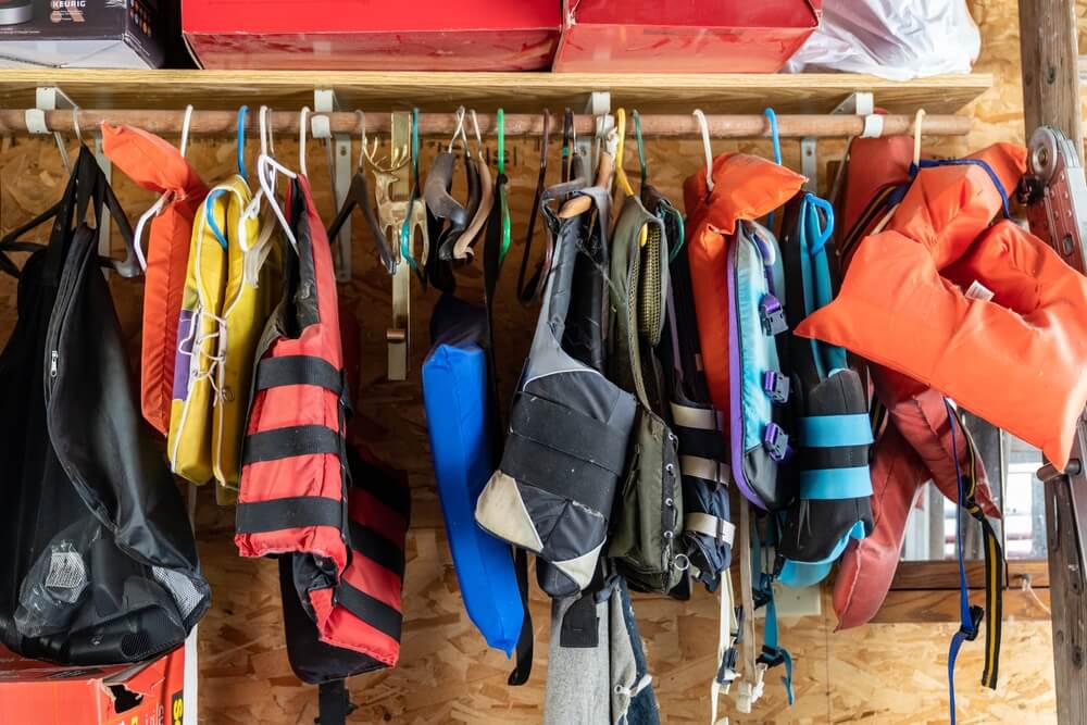 Colorful vests on hangers on a rod in a garge