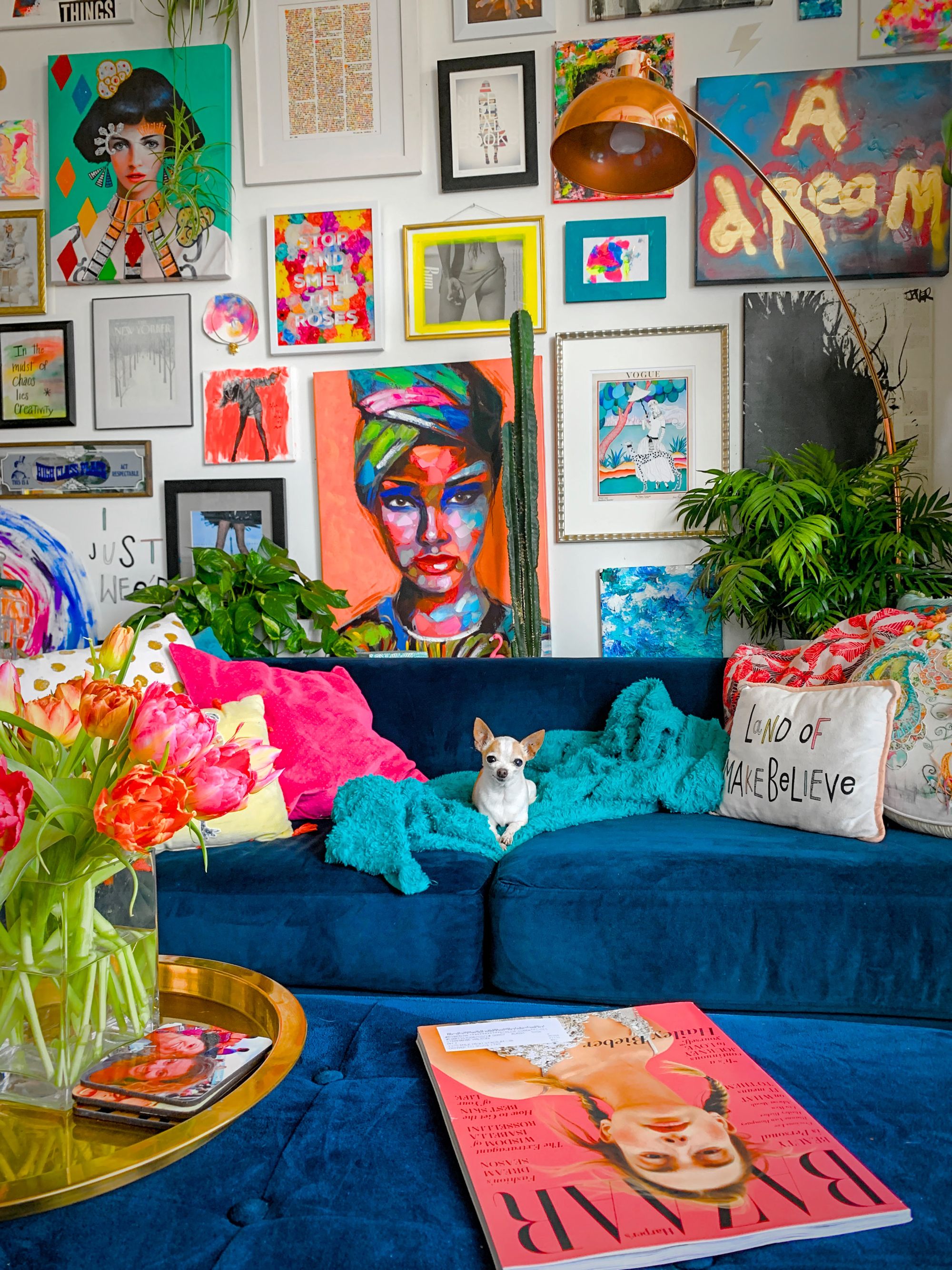 ecoración maximalista, pared galería con arte, sofá azul y perritos