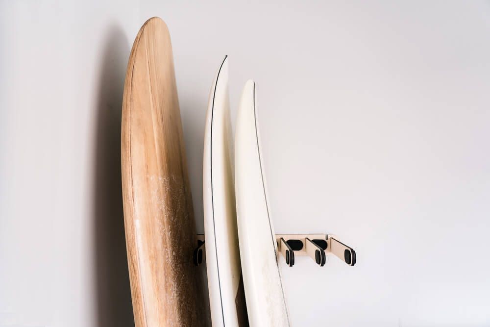 three paddle boards held up by a wall storage rack