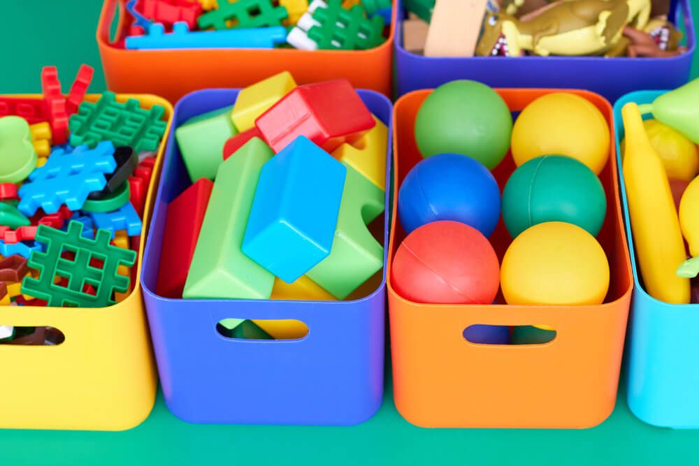Colorful plastic bins filled with plastic blocks, balls and fake fruit