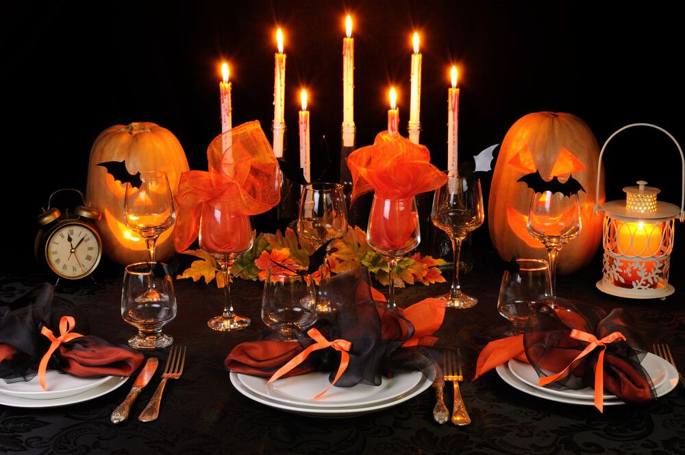 table with black table cloth, pumpkins, orange ribbons and fake bats