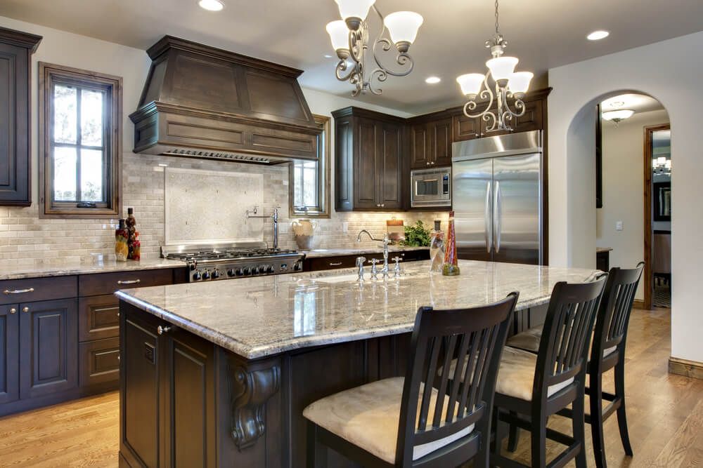 Luxury kitchen with dark cabinets, island with grantite counter and dark chairs