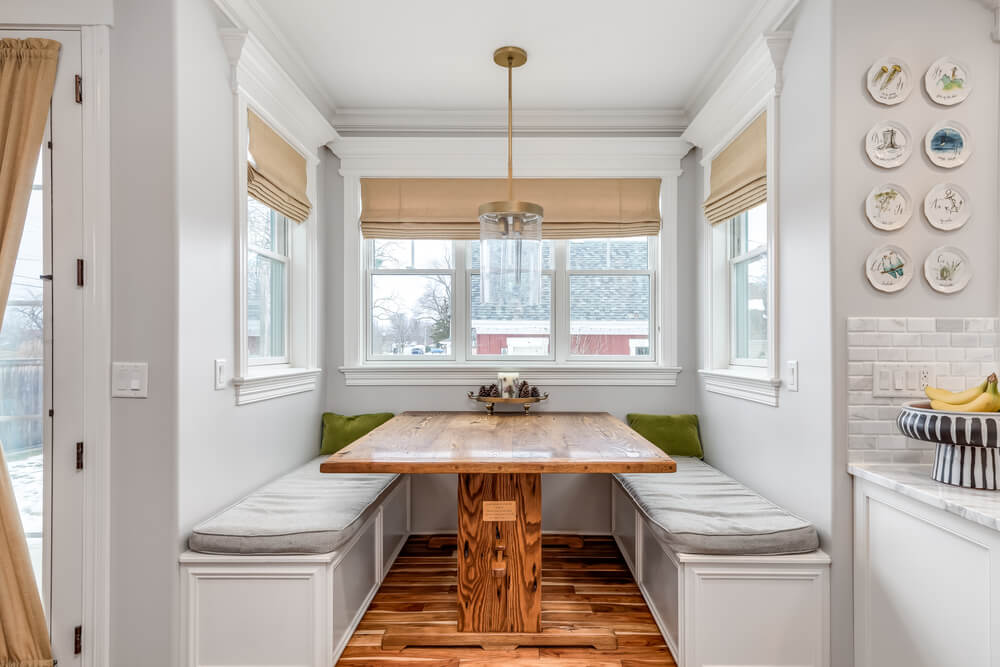 A breakfast nook with bench seating and a hardwood table built into the house.