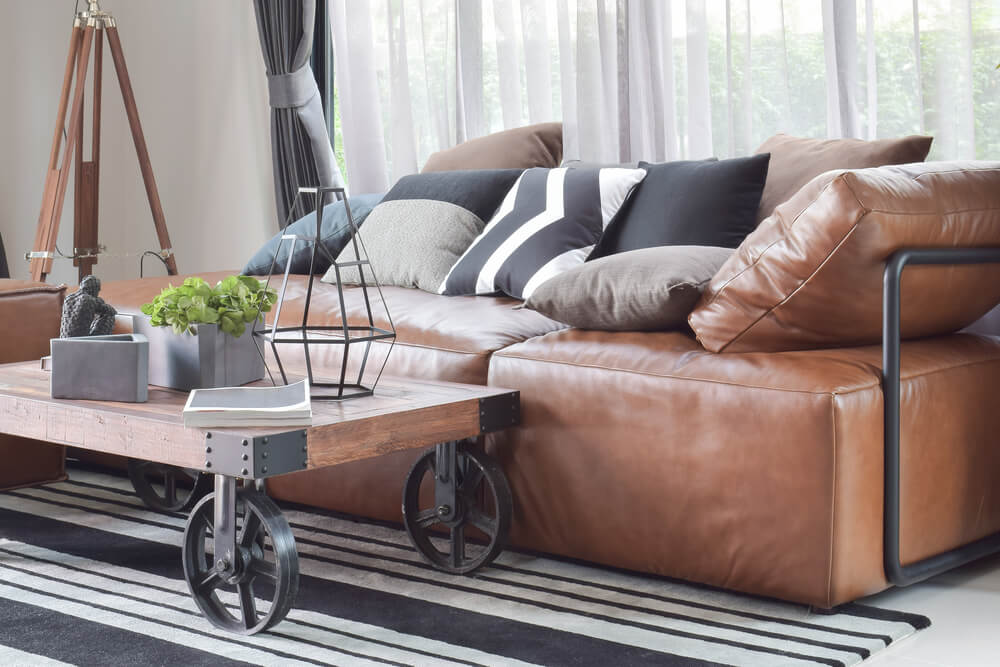sala de estar de estilo industrial con sofá de cuero y mesita de madera y acero