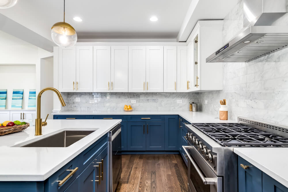 A luxurious white and blue kitchen with gold hardware