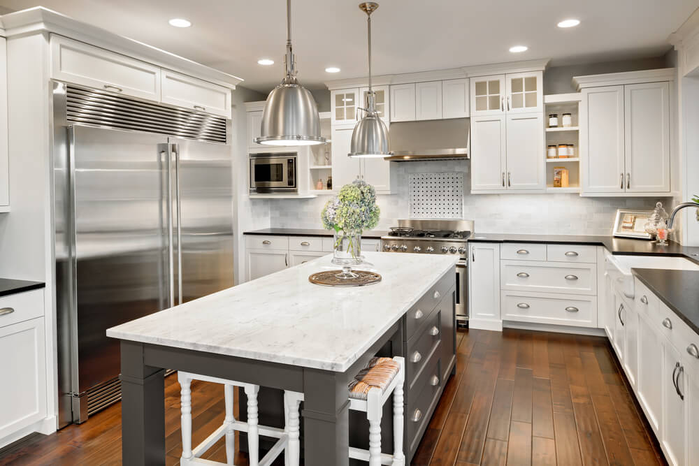 White kitchen with wood floors, stainless steel appliances and an island