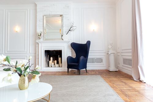 living room corner with white walls, a deep blue wing chair, and afireplace