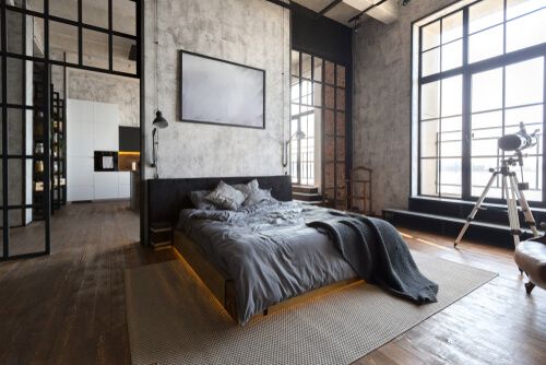 industrial bedroom with grey bedding on a queen size bed, and an astronomical telescope