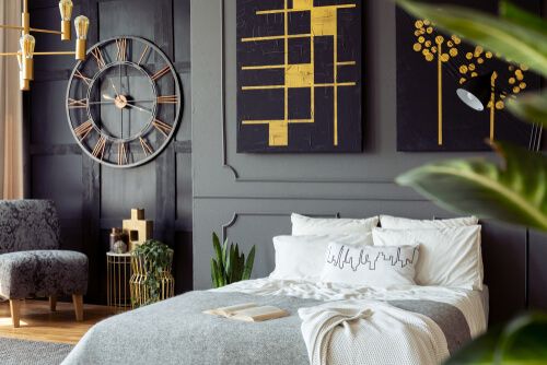 chambre à coucher élégante avec une grande horloge, lit queen size et couverture grise, oreillers blancs