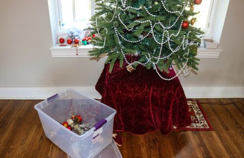petit sapin de Noël et décorations dans une boîte en plastique à côté