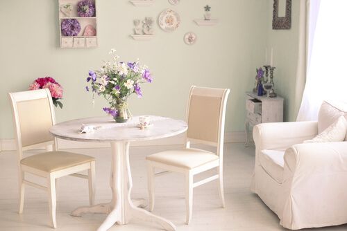 cream colored living rom with armchair, chairs, coffee table, and flowers