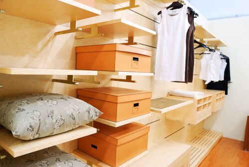 Chic walk in closet features stacked wraparound shelves filled