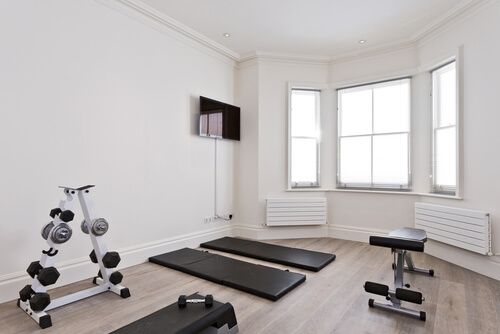 A white room set up as a home gym with mats, free weights an benches