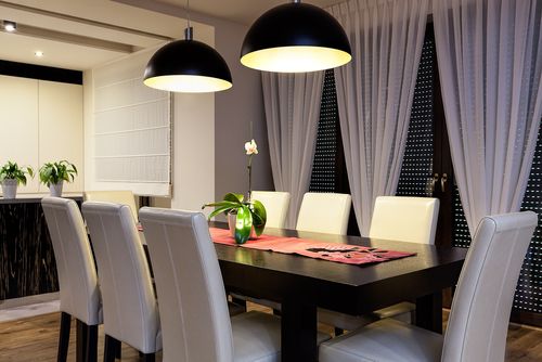 Black dome lights over a black dining room table and gray chairs