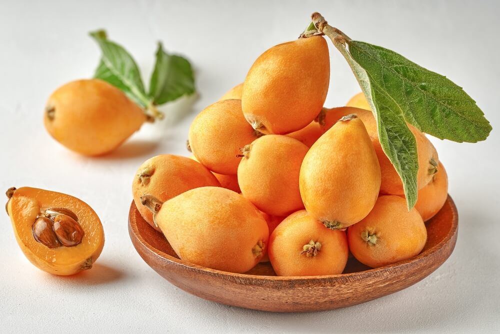 Loquat fruit in bowl with fresh leaves
