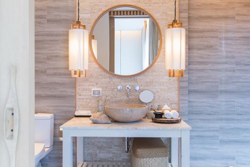 Modern bathroom with round mirror and fancy sconces