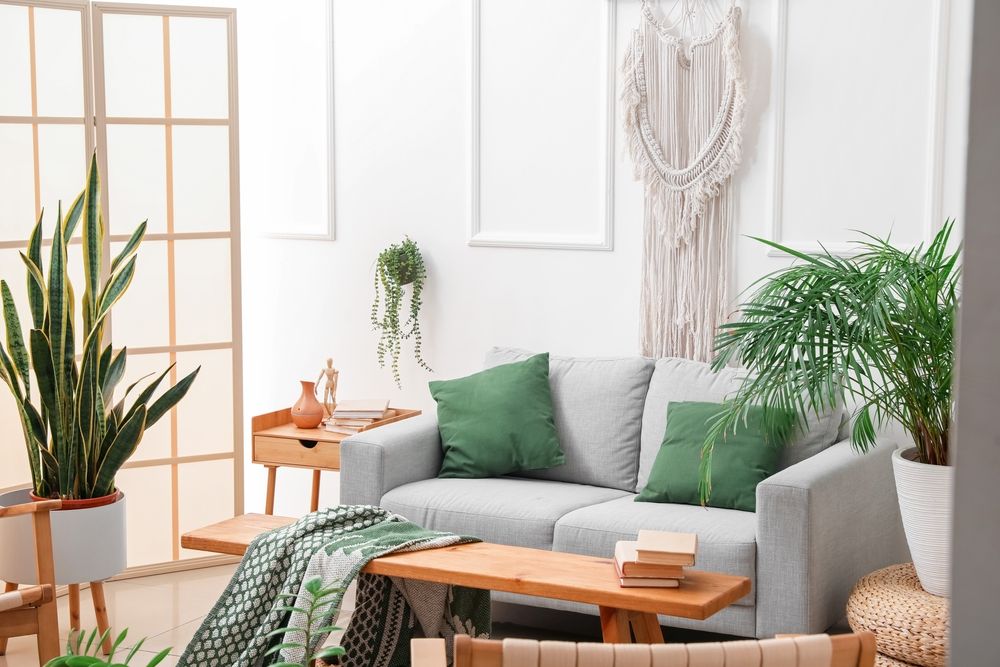 living room corner with neutral ang green colors, many plants, and wooden furniture