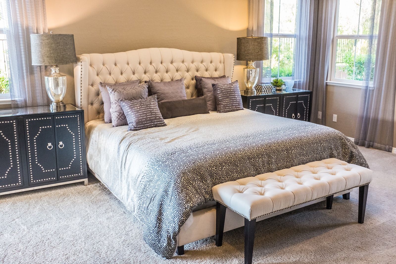 une chambre à coucher de style traditionnel, avec un grand lit et des coussins gris