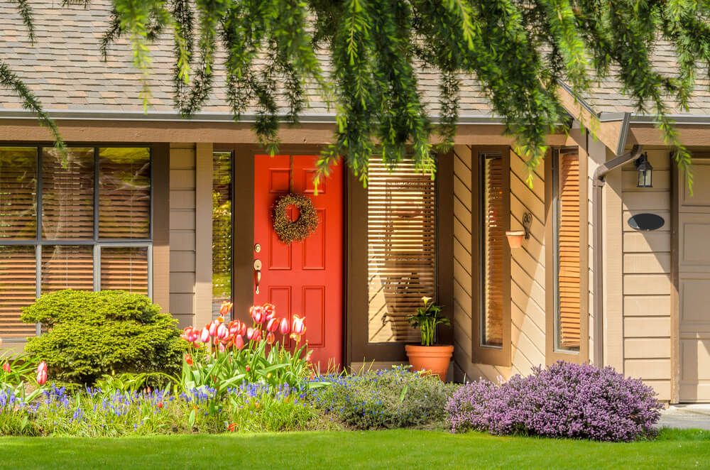 lively entry with flower beds and a red entry door