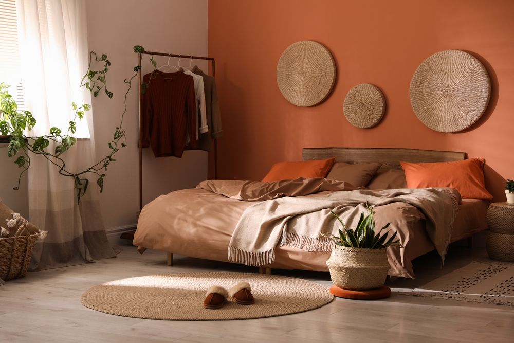 chambre à coucher boho avec plantes, murs orange et accessoires en rotin