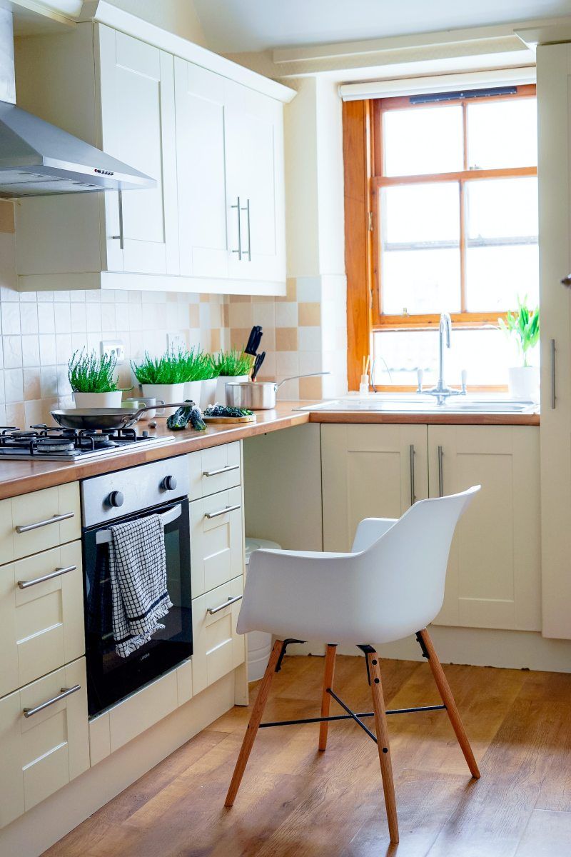 kleine Küche mit orangefarbenen Elementen, Pflanzen und einem weißen Stuhl in der Mitte