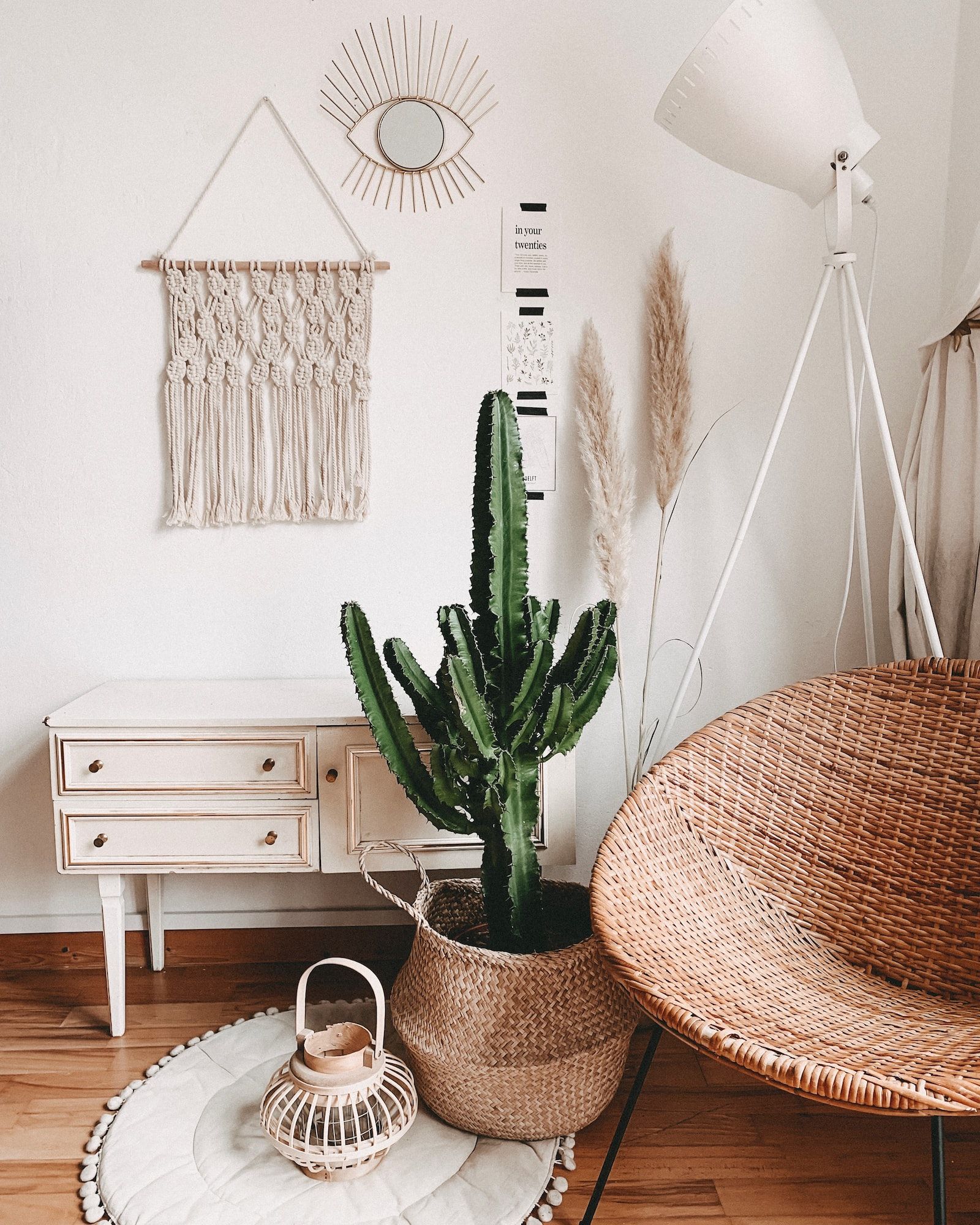Boho-Zimmerecke, ein Bambusstuhl, ein großer Kaktus, ein weißer Schrank und eine weiße Lampe