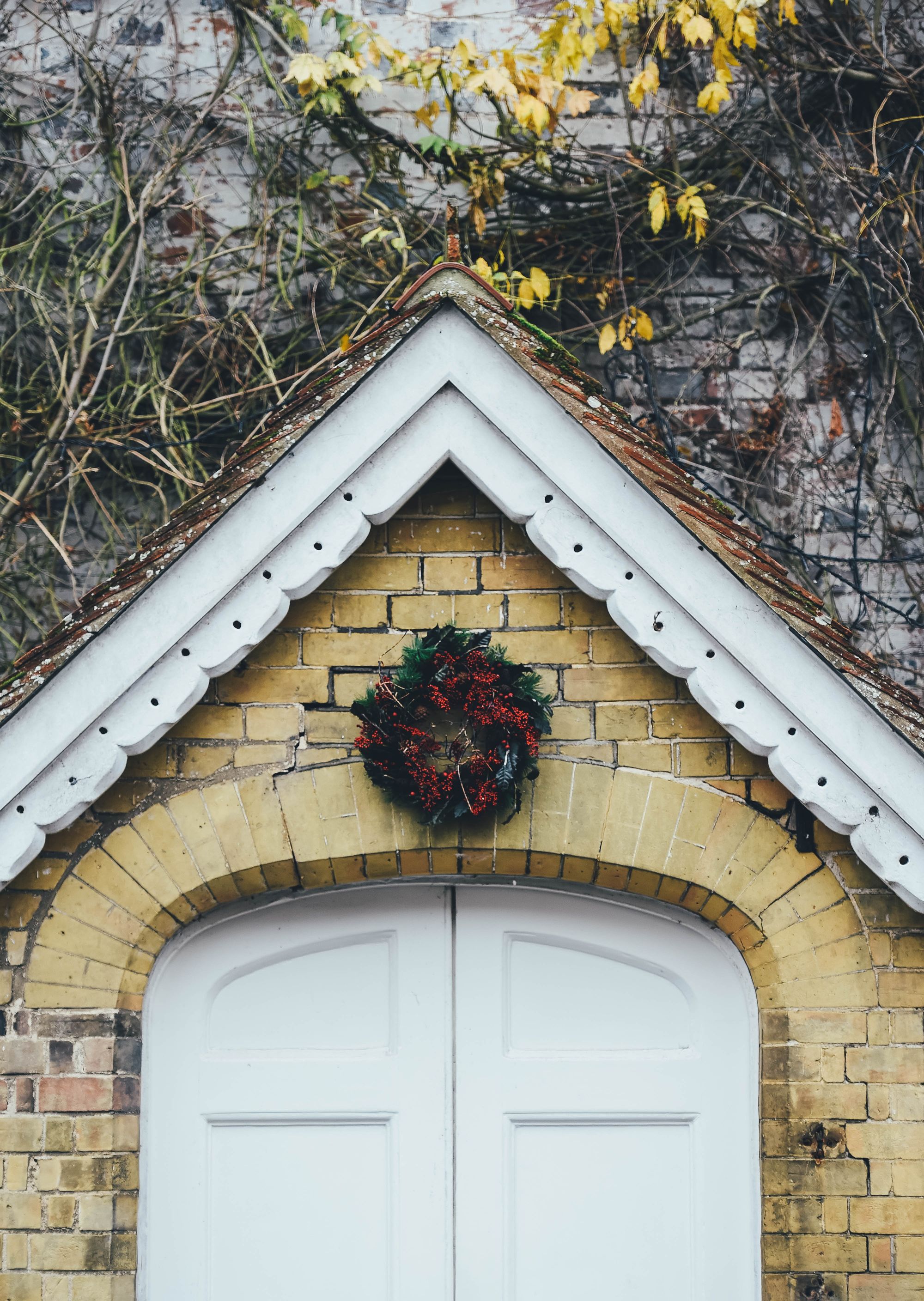 puerta principal en fachada de casa de piedra con guirnalda de navidad
