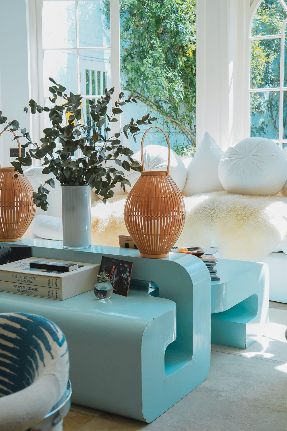 intérieur maximaliste avec une table géométrique bleu clair, des plantes et des matériaux naturels