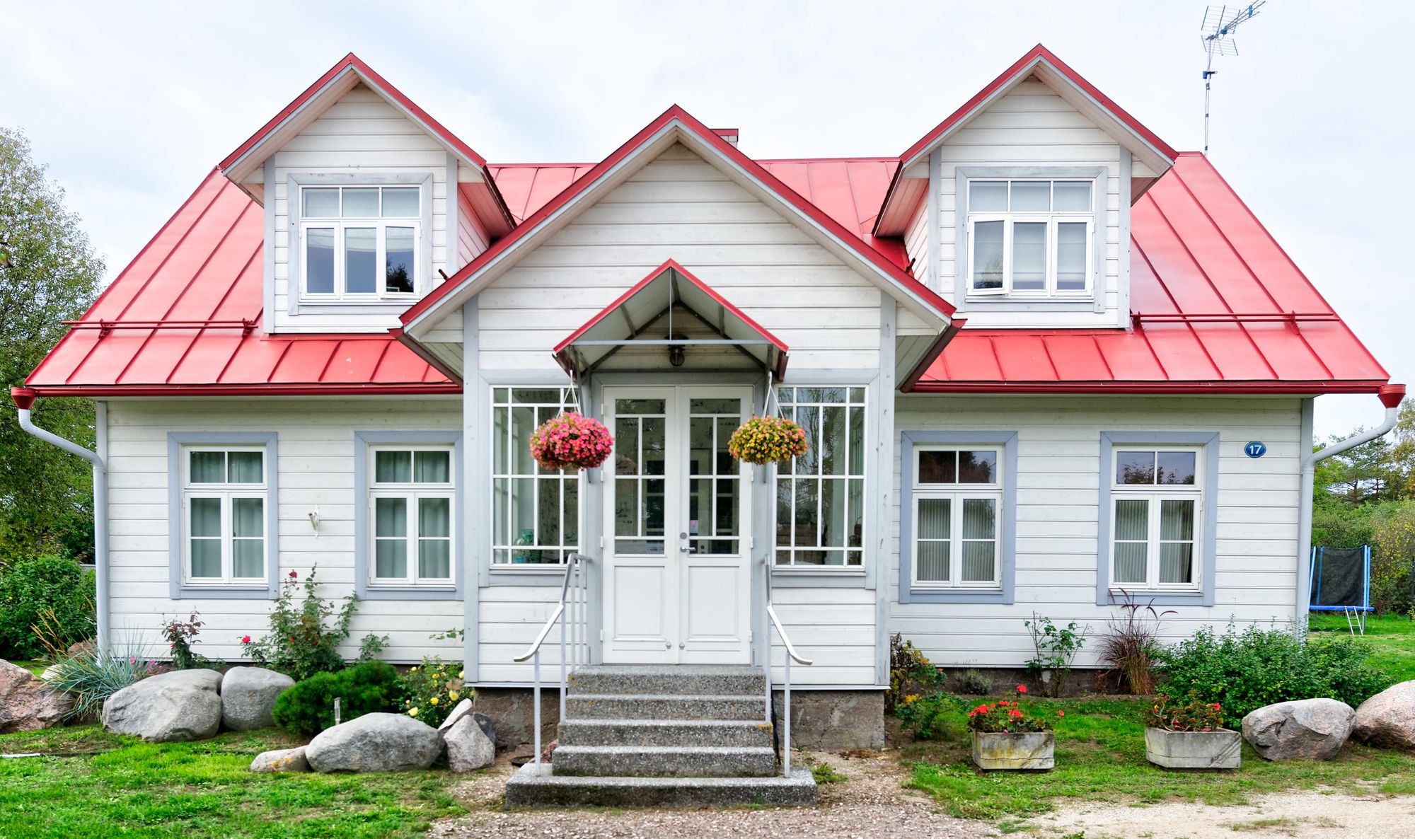diseño de casa de dos plantas fachada hermosa y clásica con tejado rojo y flores