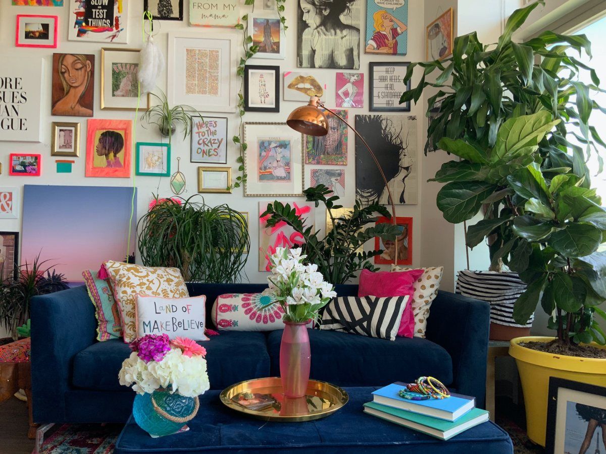 décor maximalist avec un canapé bleu, beaucoup de coussins et photos murales, plantes