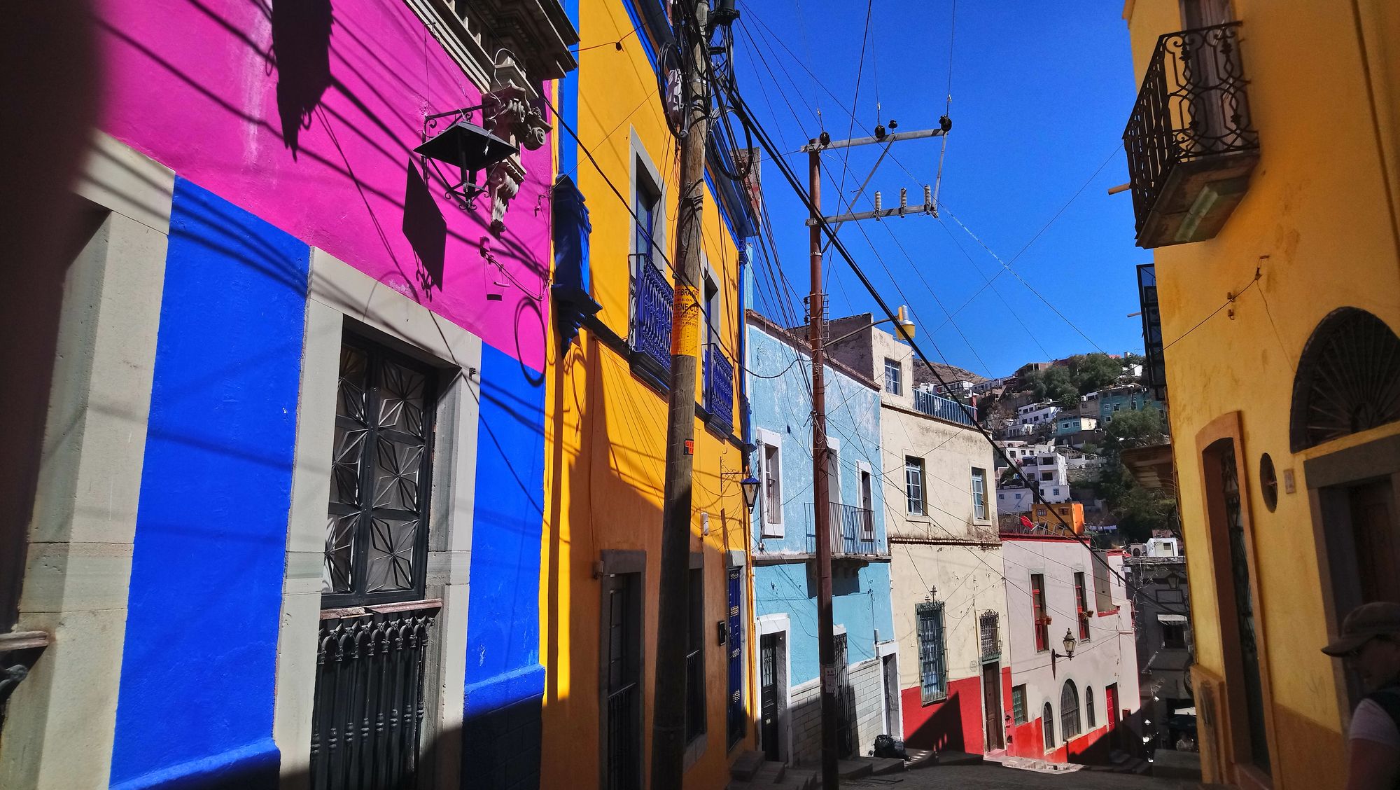 calle en maxico con fachadas de casas pequeñas de dos pisos de colores