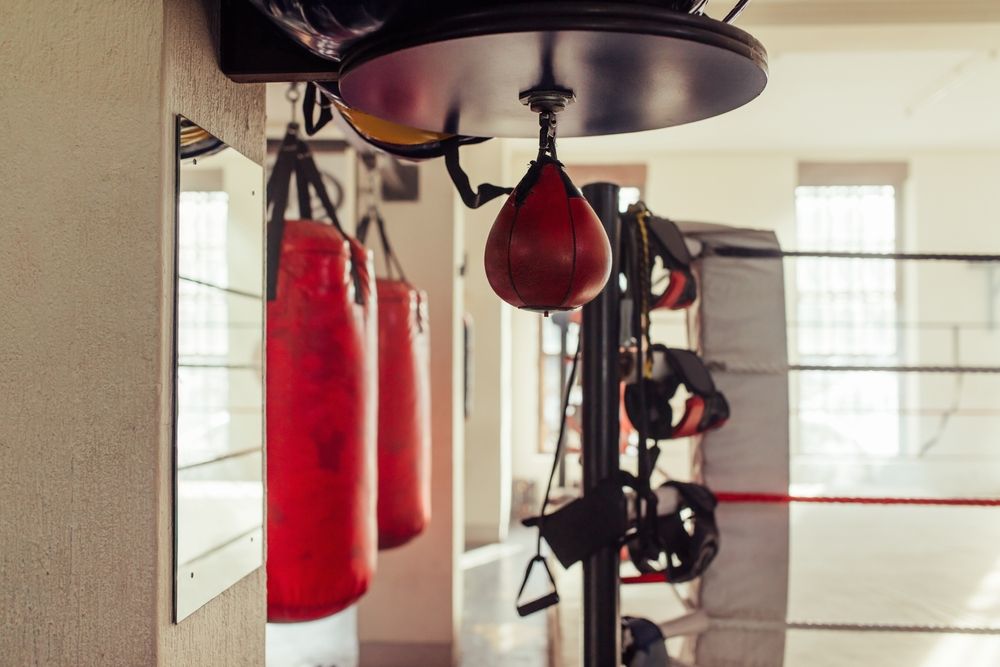 Small red punching bag hanging near other training equipment in a boxing gym