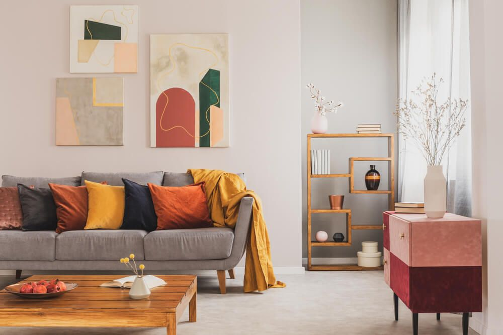 яркая гостиная с картинами и серым диваном с оранжевыми подушками
