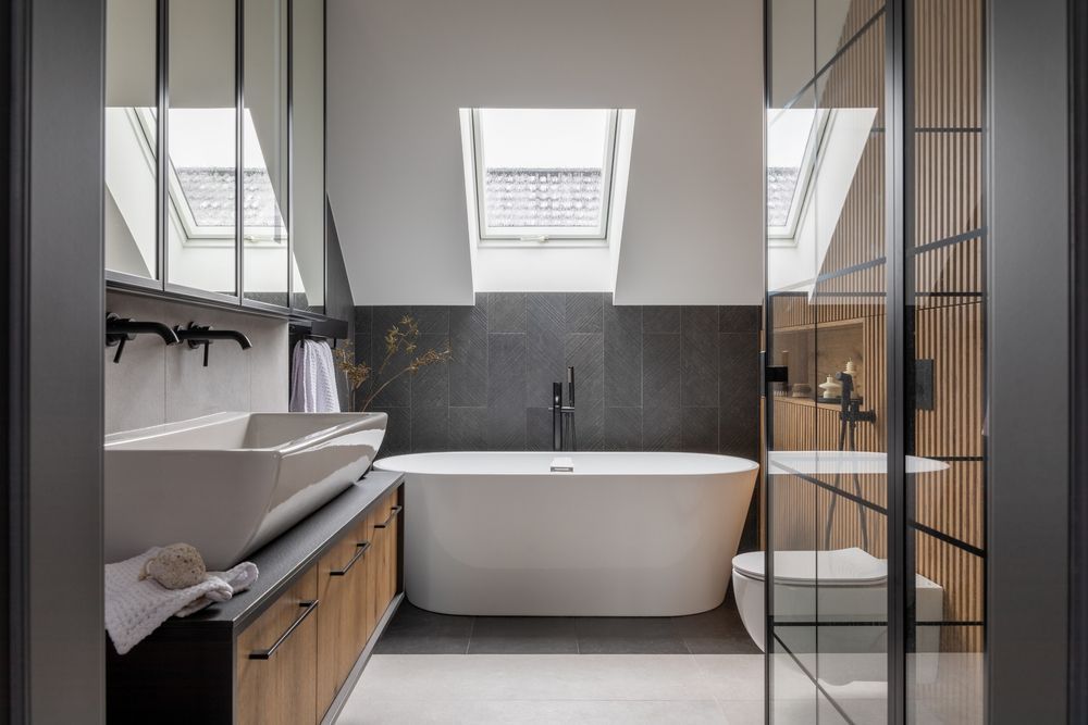 baño de diseño minimalista con bañera blanca y paredes de piedra y madera