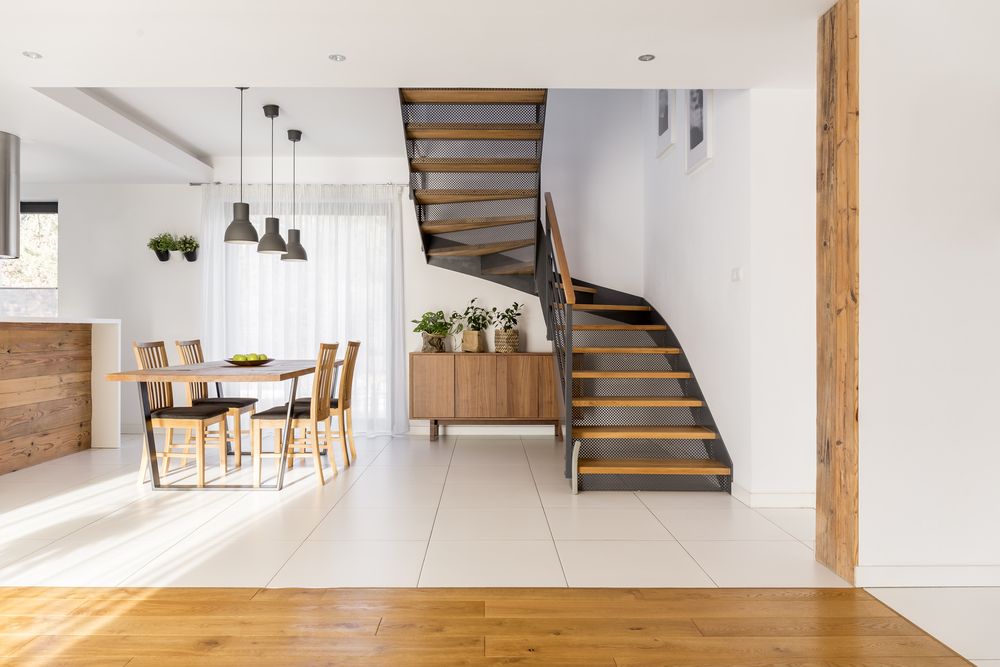 minimalistisches Esszimmer mit einem Tisch und 4 Holzstühlen und einer Treppe