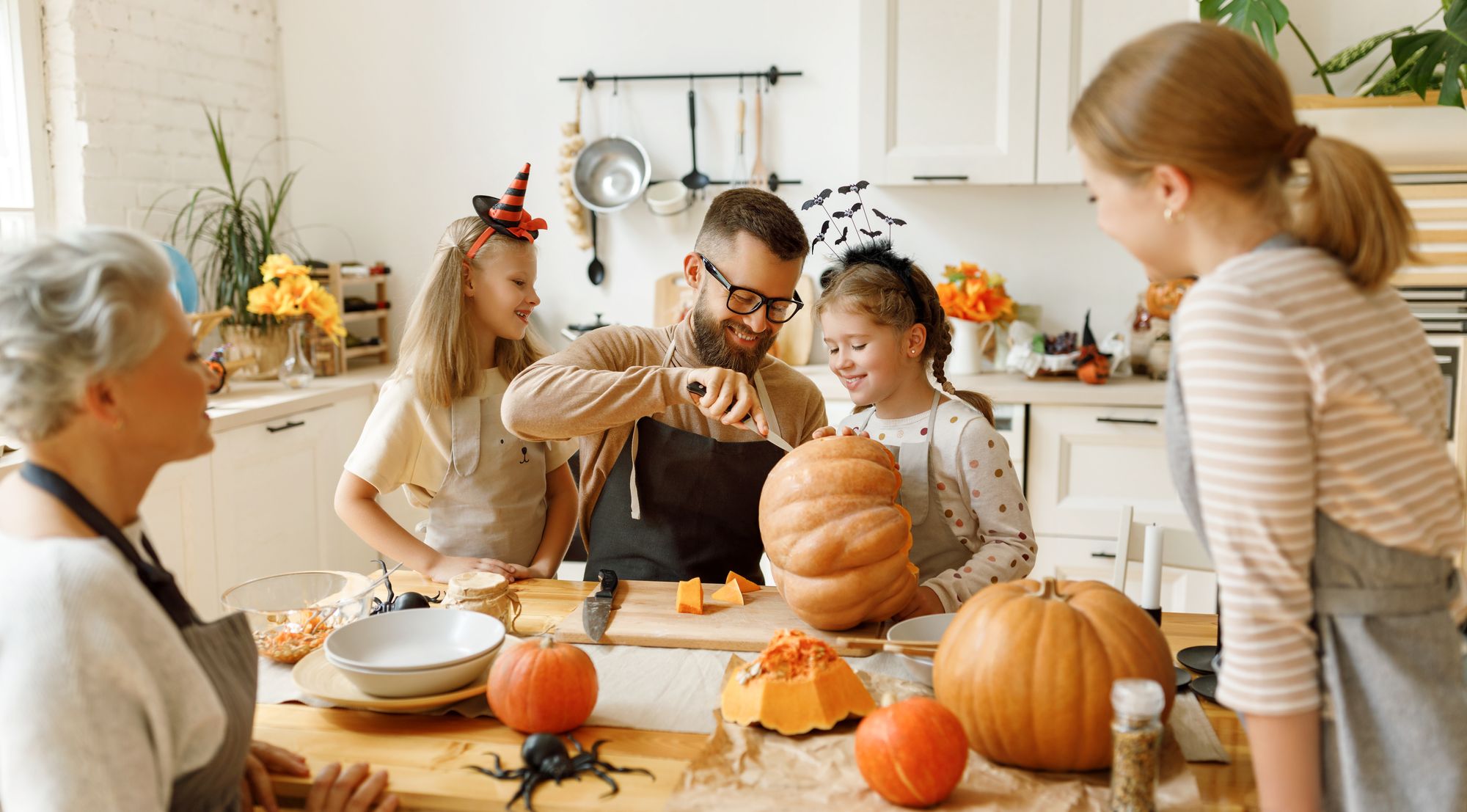 fünfköpfige familie schnitzt kürbisse für halloween in der küche