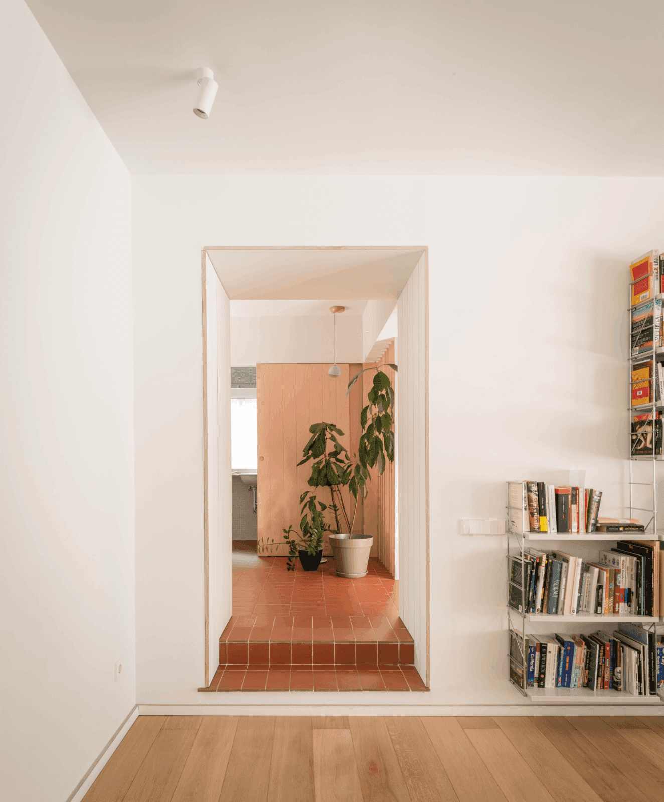 sala de estar con librería y hall de entrada con acabados de cerámica y plantas