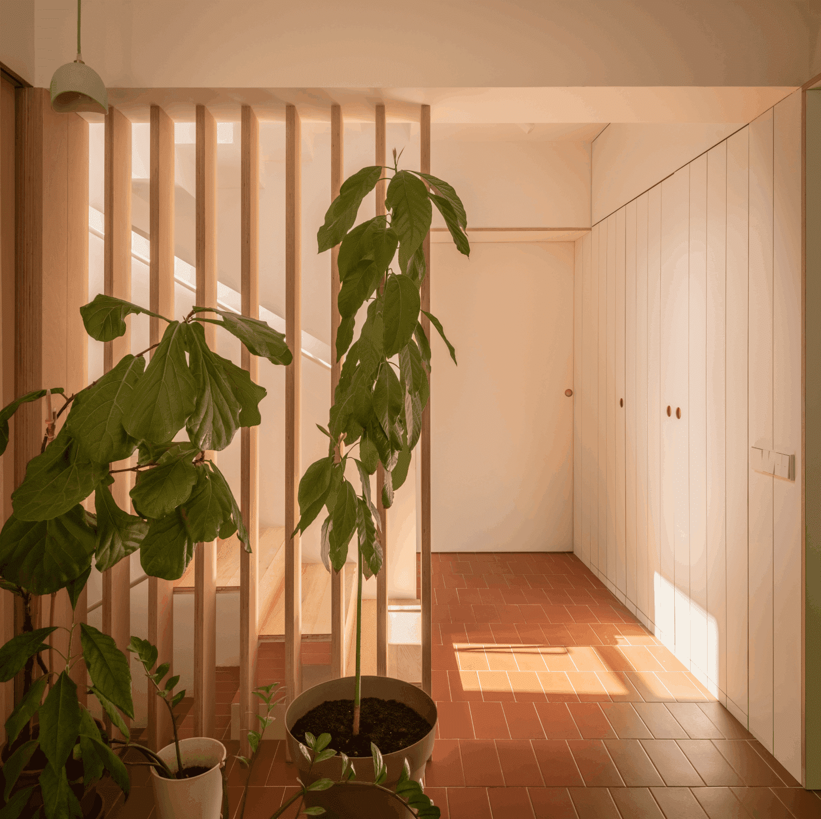 hall de entrada con acabados de cerámica, plantas y escaleras de madera