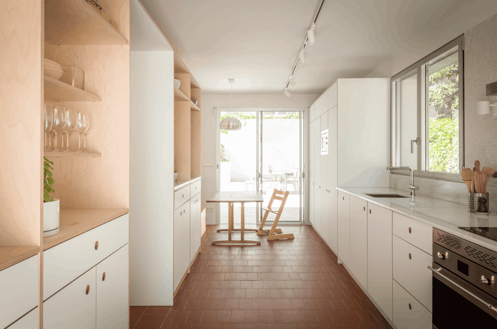 Cocina blanca con suelo acabados en cerámica rojiza y muebles de madera
