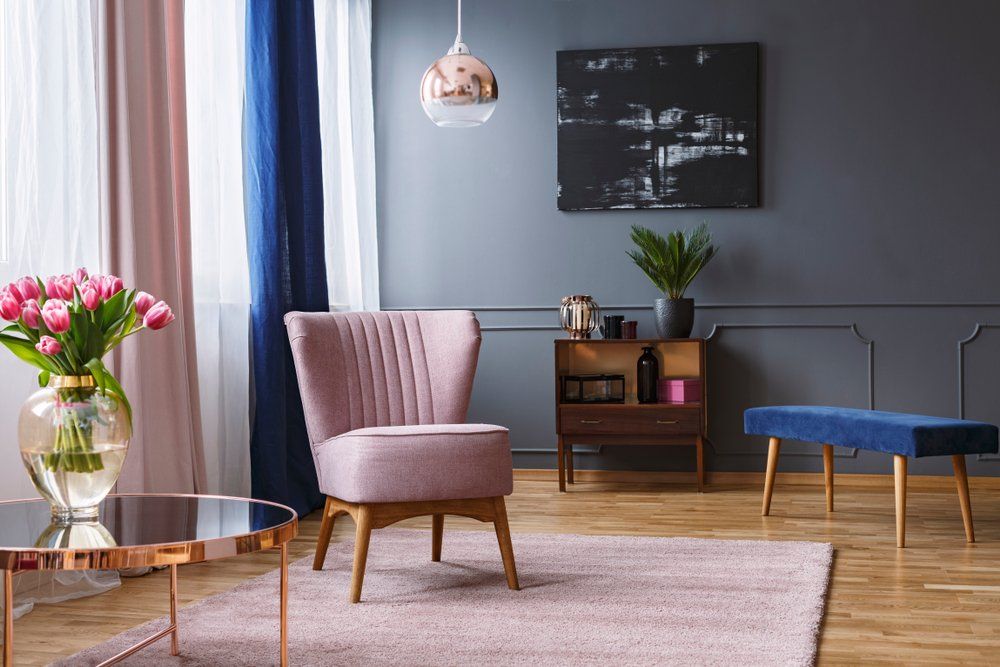 pink armchair standing on a rug and under a lamp in spacious living room